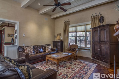 A living room with a brown leather couch and a wooden coffee table.