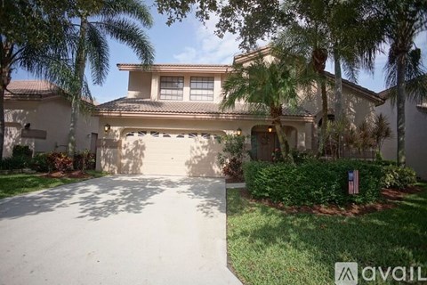 A house with a driveway and palm trees in front.