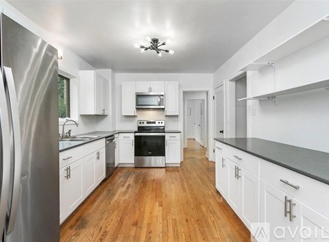 A kitchen with white cabinets and a wooden floor.