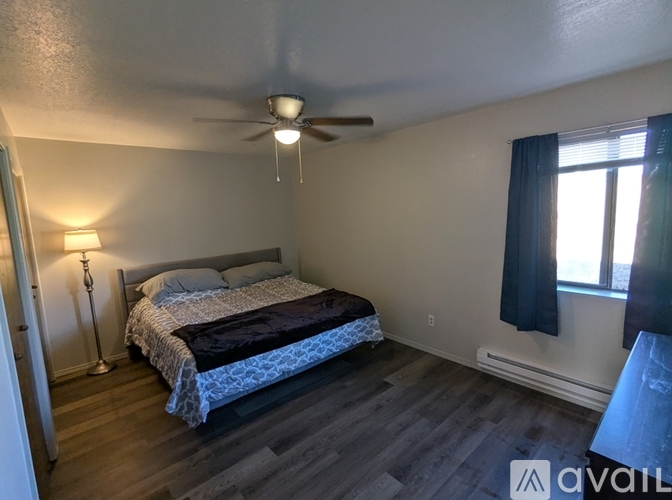 A room with wooden flooring and white walls, with a door on the right side.