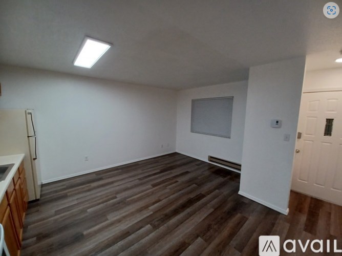 A room with wooden flooring and white walls, with a door on the right side.