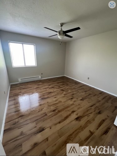 A room with wooden flooring and a ceiling fan.
