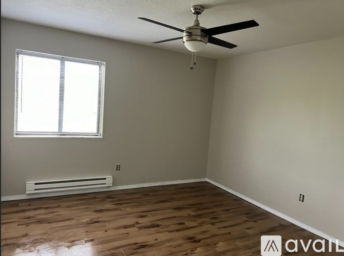 A room with a ceiling fan and a window with blinds.