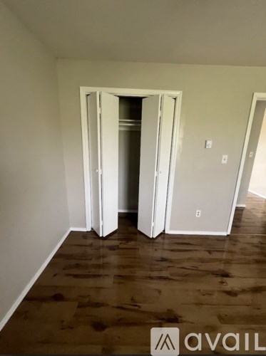 A room with a white door and wooden flooring.