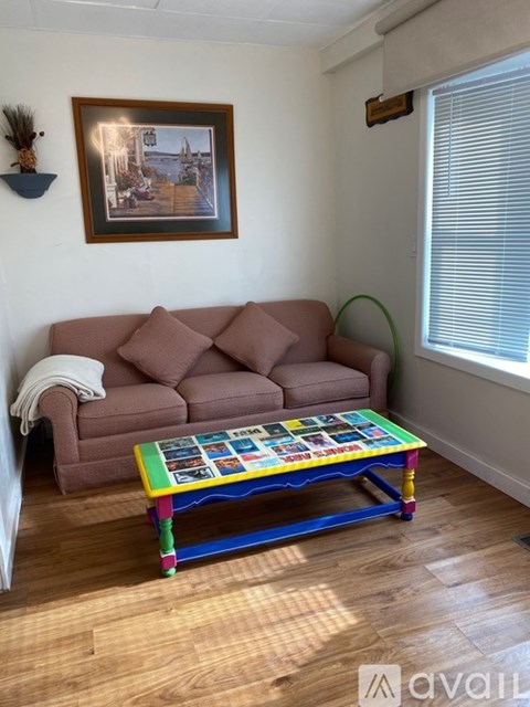 A living room with a brown couch, a coffee table with a puzzle on it, and a picture frame on the wall.
