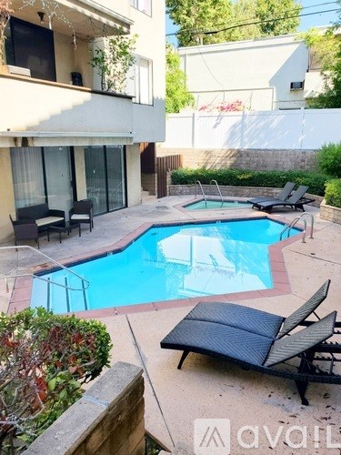 A pool with a black chair and a building in the background.