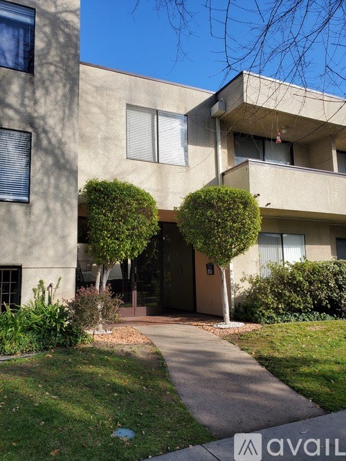 A building with a brown door and windows with bushes in front.