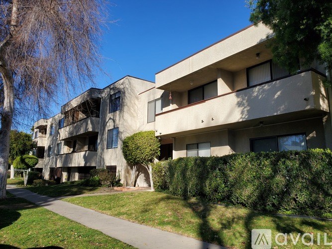 A modern building with a balcony and a hedge in front.