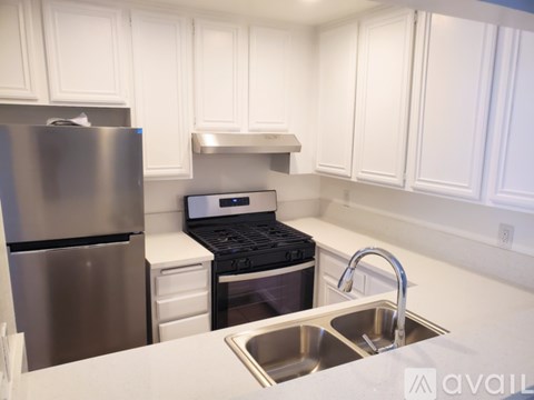 A kitchen with white cabinets and a stainless steel refrigerator.
