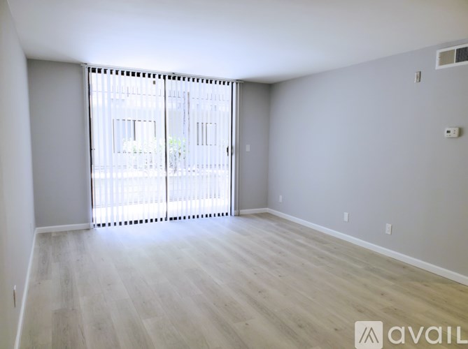 A spacious room with a sliding door and wooden flooring.