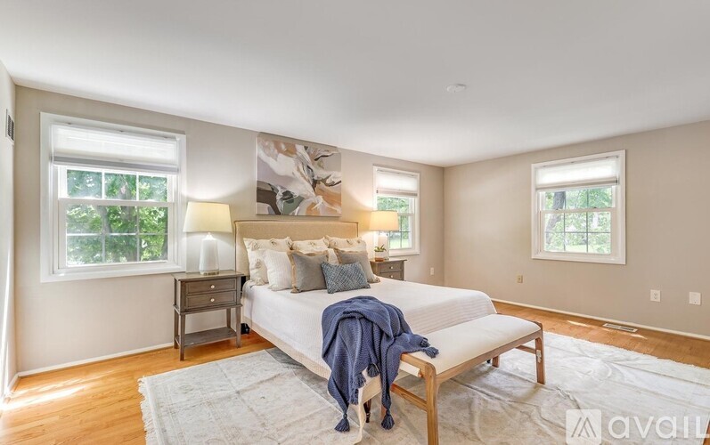 A bedroom with a bed, nightstands, and windows.