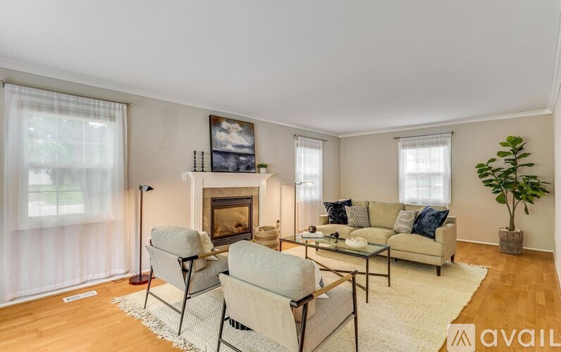 A living room with a fireplace, two chairs, and a couch.