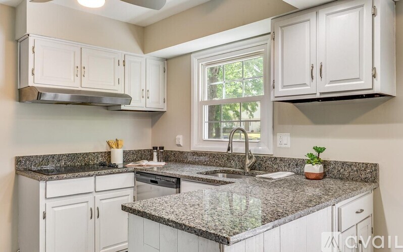 A kitchen with white cabinets and granite countertops.