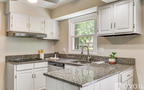 A kitchen with white cabinets and granite countertops.