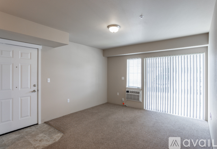 A room with a carpeted floor and a window with blinds.