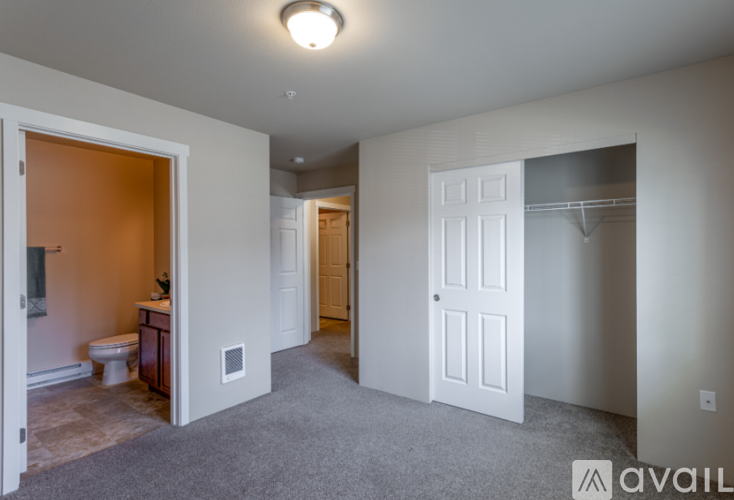 A spacious room with a toilet and sink visible through an open door.