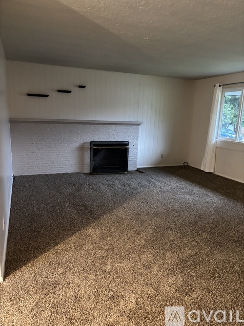 A living room with a fireplace and carpeted floor.
