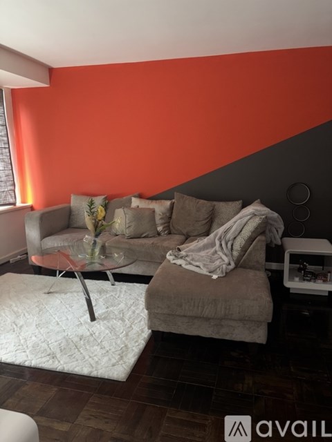 A living room with a grey couch and a red wall.