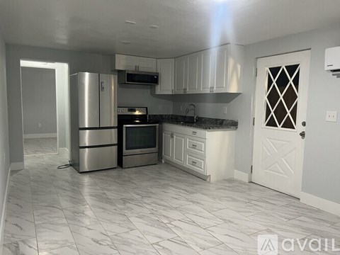 A kitchen with white cabinets and a black countertop.