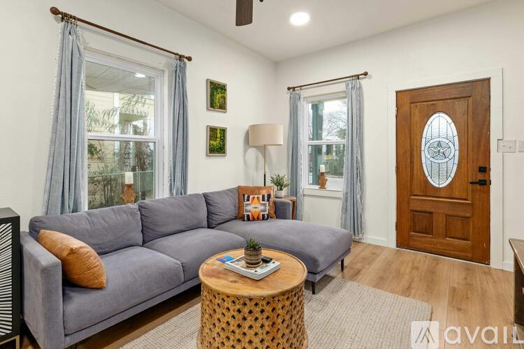 A bedroom with a bed, a chair, a ceiling fan, and a window with yellow curtains.