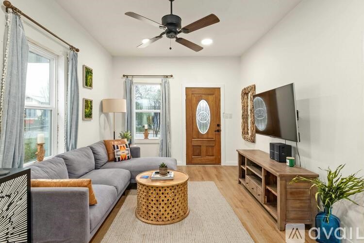 A living room with a grey couch, a wooden coffee table, a flat screen TV, and a ceiling fan.