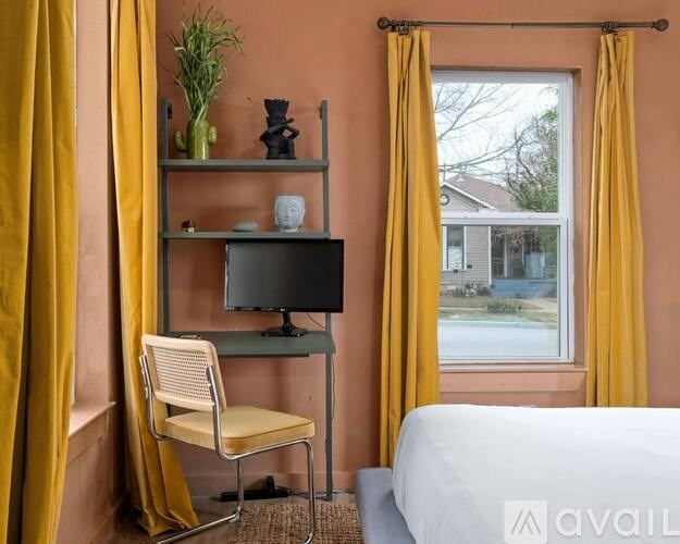 A room with a television, chair, and shelf with a window overlooking a street.