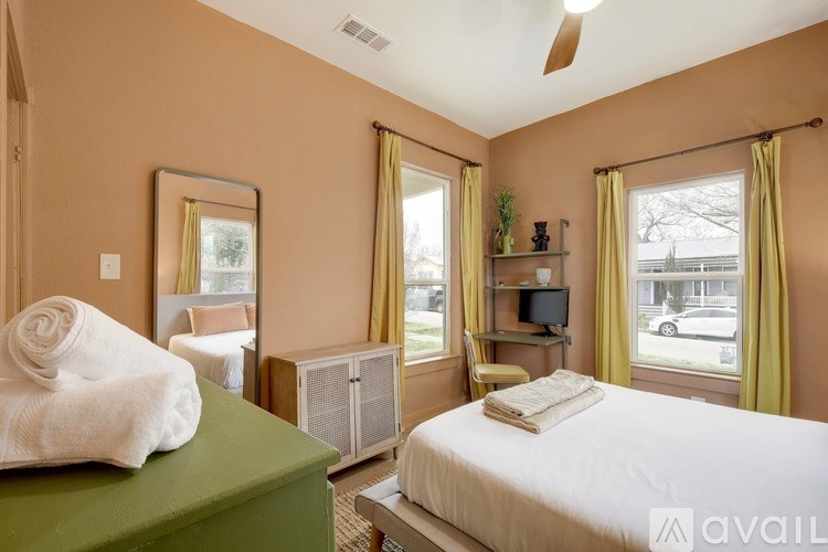 A bedroom with a bed, a chair, and a fan.