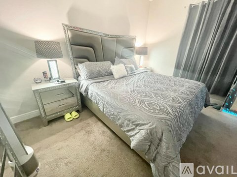 A bedroom with a large bed and a nightstand with a lamp.