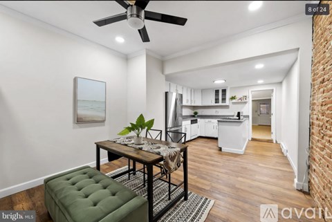 A modern kitchen with a dining table and chairs in the foreground and a brick wall on the right.