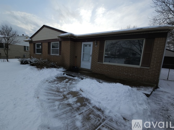 A house with a white door and windows is surrounded by snow.