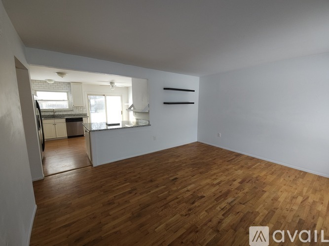 Empty room with wooden flooring and white walls.