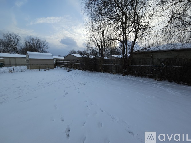 A snowy landscape with a fence and a building in the background.
