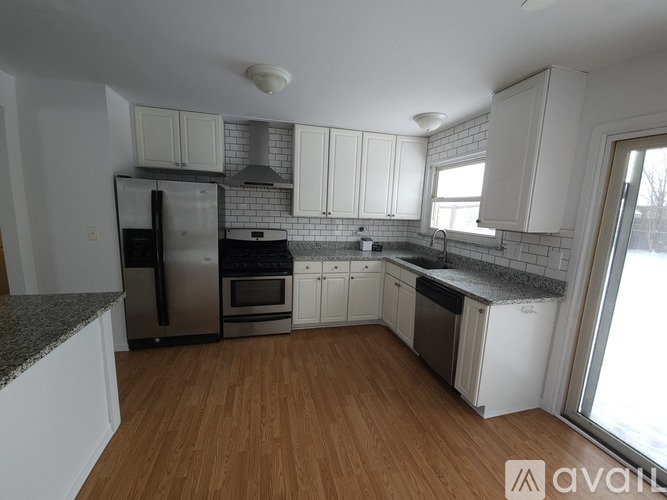 A kitchen with white cabinets and a wooden floor.