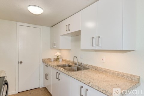 A kitchen with white cabinets and a granite countertop.