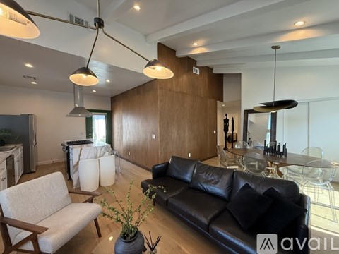 A modern living room with a black leather couch and a wooden chair.
