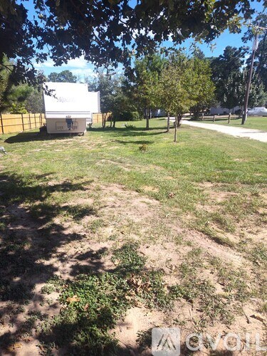 A white trailer is parked in a grassy field.