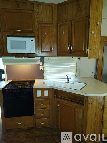 A kitchen with wooden cabinets and a white microwave above the stove.