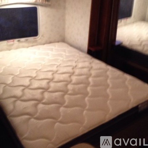 A bed with a white quilted cover is in the image.