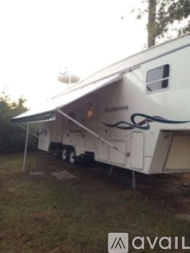 A Budweiser RV is parked in a grassy area.