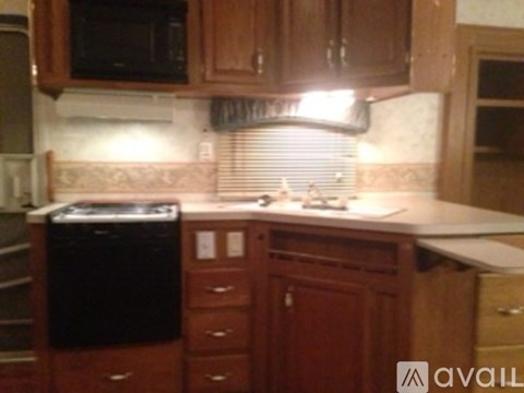 A kitchen with wooden cabinets and a black dishwasher.