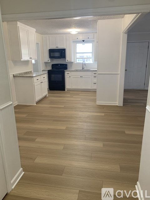 A kitchen with white cabinets and a black oven.