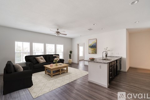 A living room with a black couch, a coffee table, and a painting on the wall.