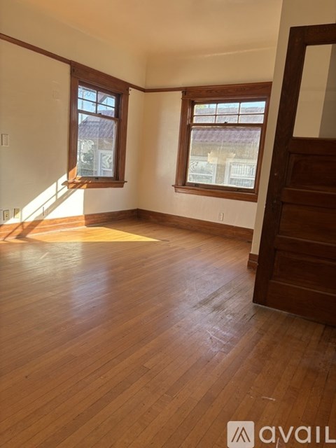 A room with wooden floors and two windows.