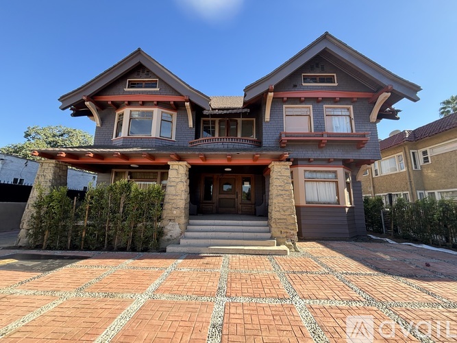 A two-story house with a red brick driveway in front.