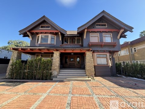 A two-story house with a red brick driveway in front.