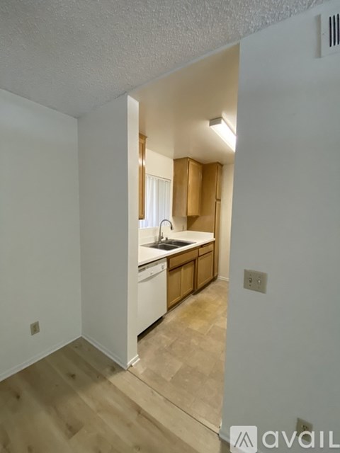 A kitchen area with wooden cabinets and a white dishwasher.