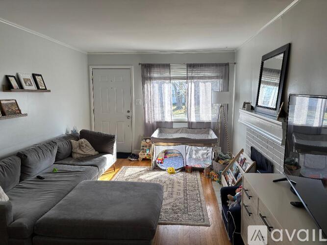 A living room with a grey couch and a fireplace.