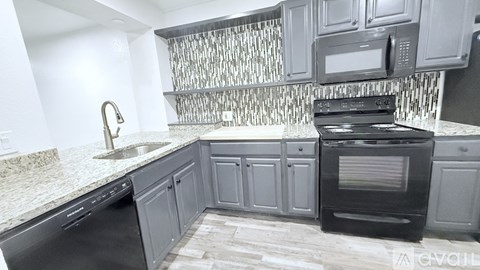A kitchen with a black oven and grey cabinets.