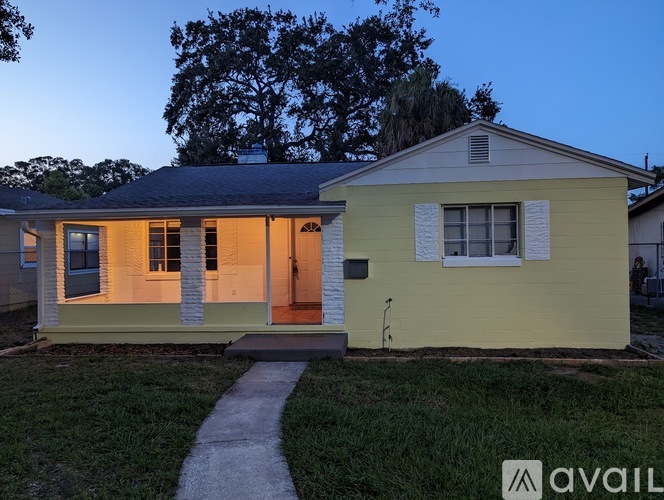 A yellow house with a porch and a small front yard.