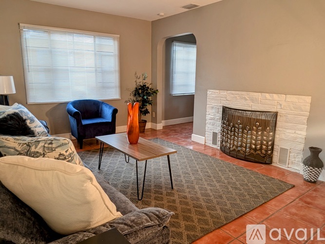A living room with a grey couch, a white fireplace, and a brown rug.
